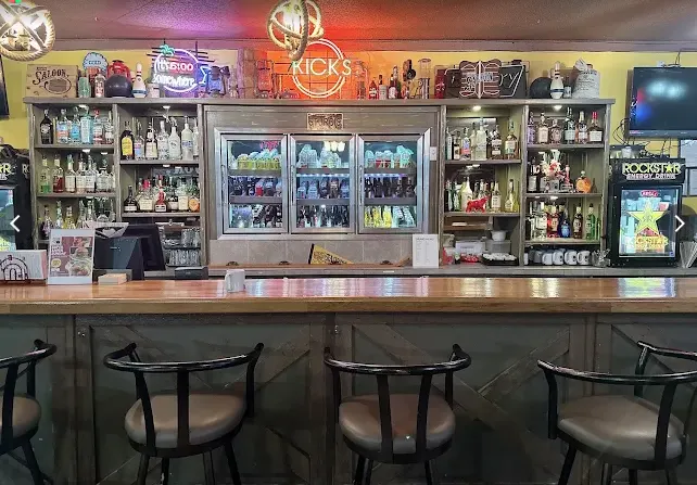 The fully-stocked bar at Kicks Saloon with the glowing Kicks neon sign