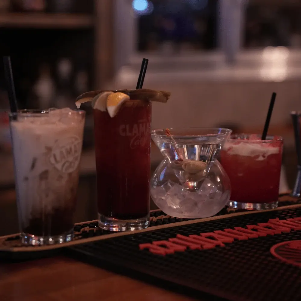 Caesars, a martini and cocktails lined up on the bar rail at Kicks Saloon